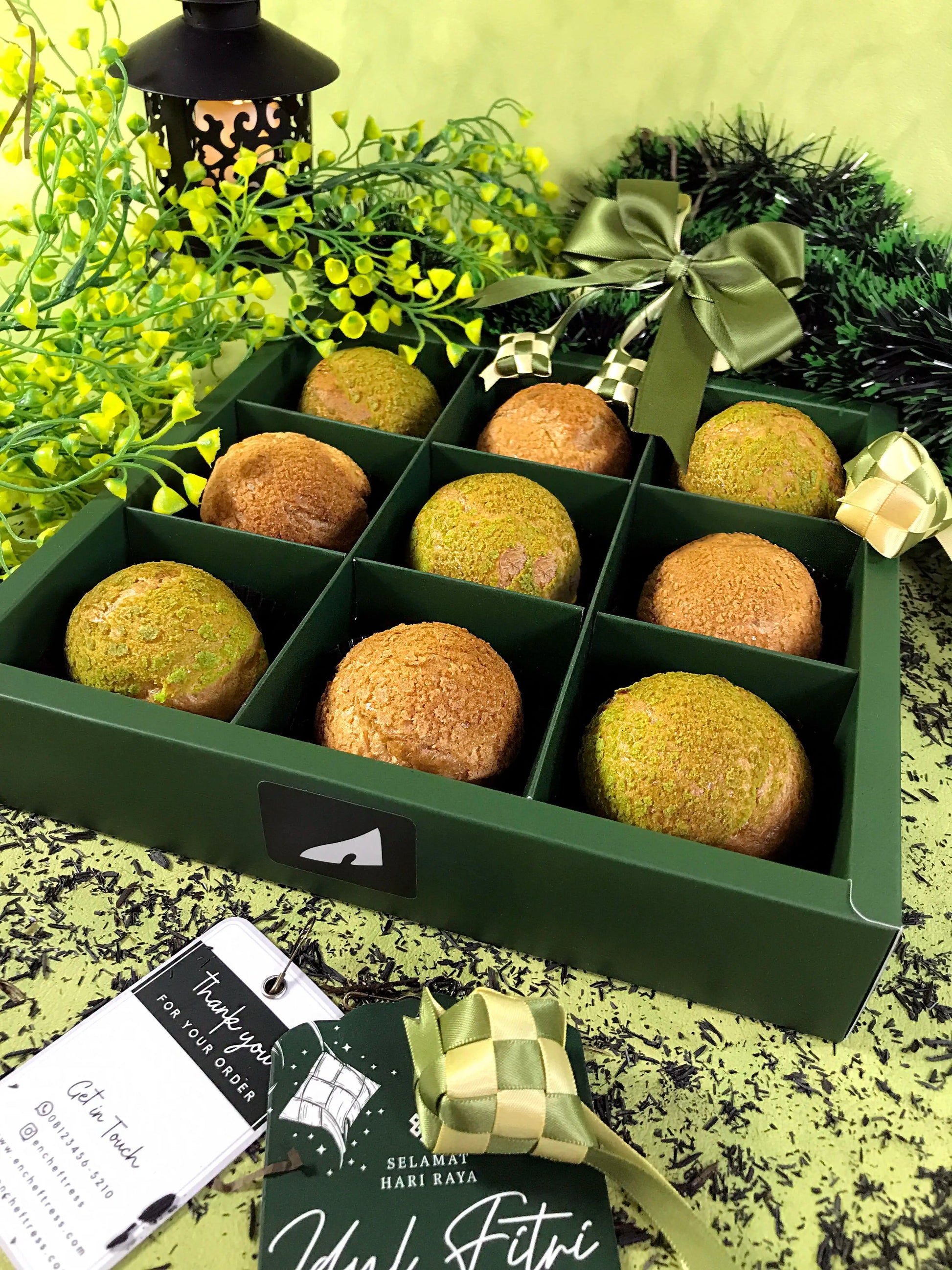 A green box containing nine choux au craquelin pastries, decorated with a green ribbon and a 'Selamat Hari Raya Idul Fitri' tag.